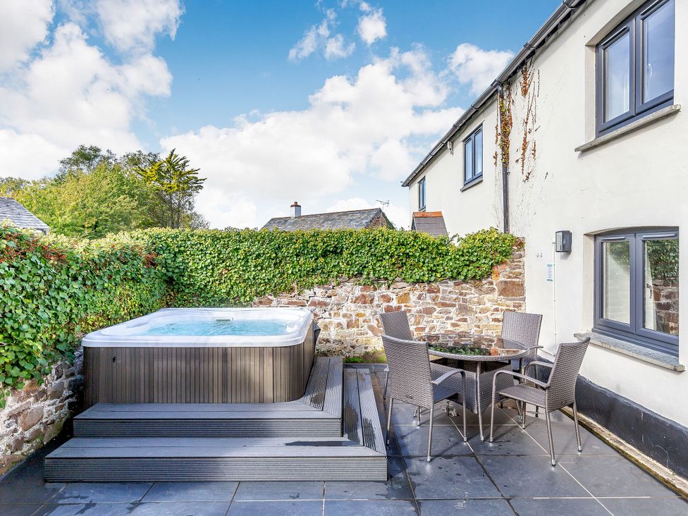 An outdoor area with a hot tub and seating at Summerleaze Cottage 2 Spa in Bude