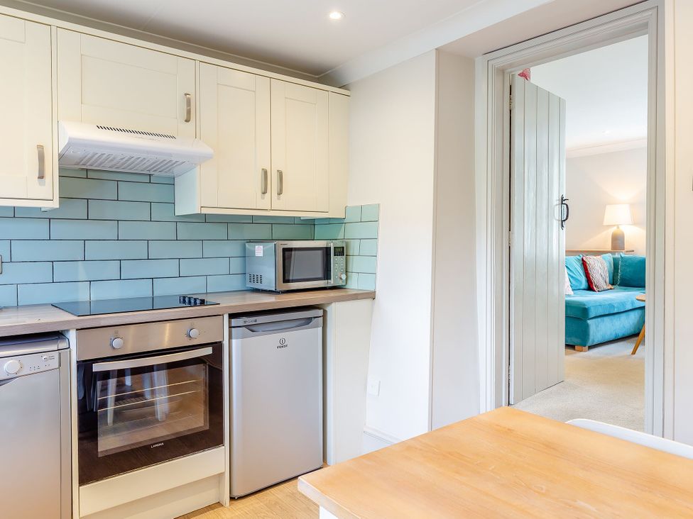 A kitchen with appliances and wood table at Summerleaze Cottage 2 Spa Bude