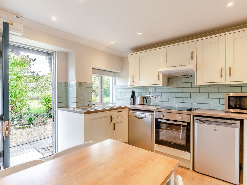 A kitchen with appliances and a table at Summerleaze Cottage 2 Spa in Bude