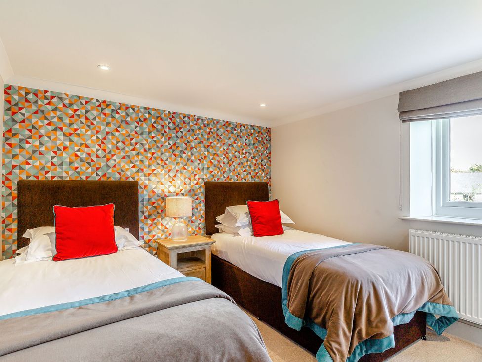 A bedroom with two beds and a lamp at Summerleaze Cottage 2 Spa in Bude