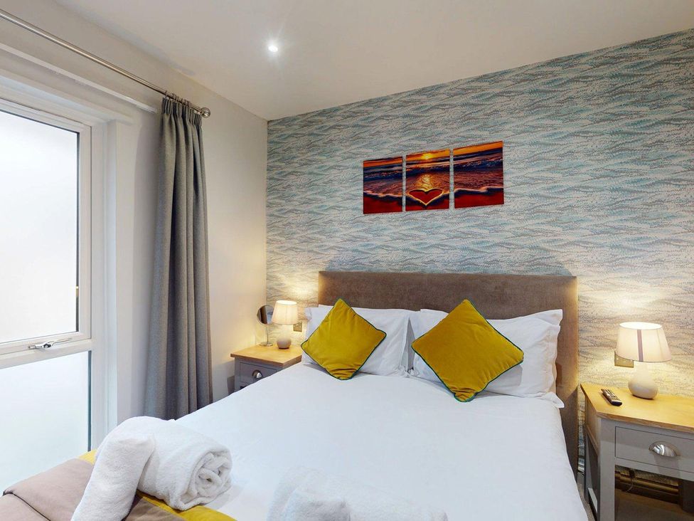 A bedroom with a bed and artwork on the wall at Summerleaze Cottage 2 Spa in Bude