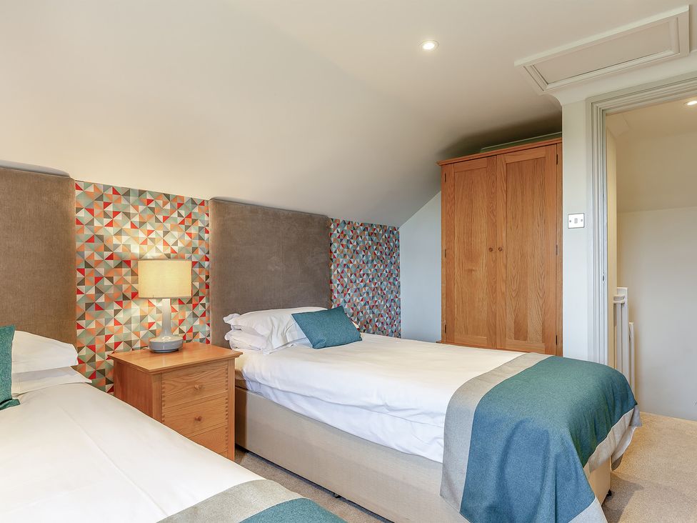 A bedroom with two beds and a bedside table at Summerleaze Cottage 2 Spa in Bude