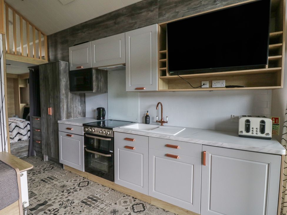 A kitchen with cabinets, sink, and appliances at The Family Pod in Swansea