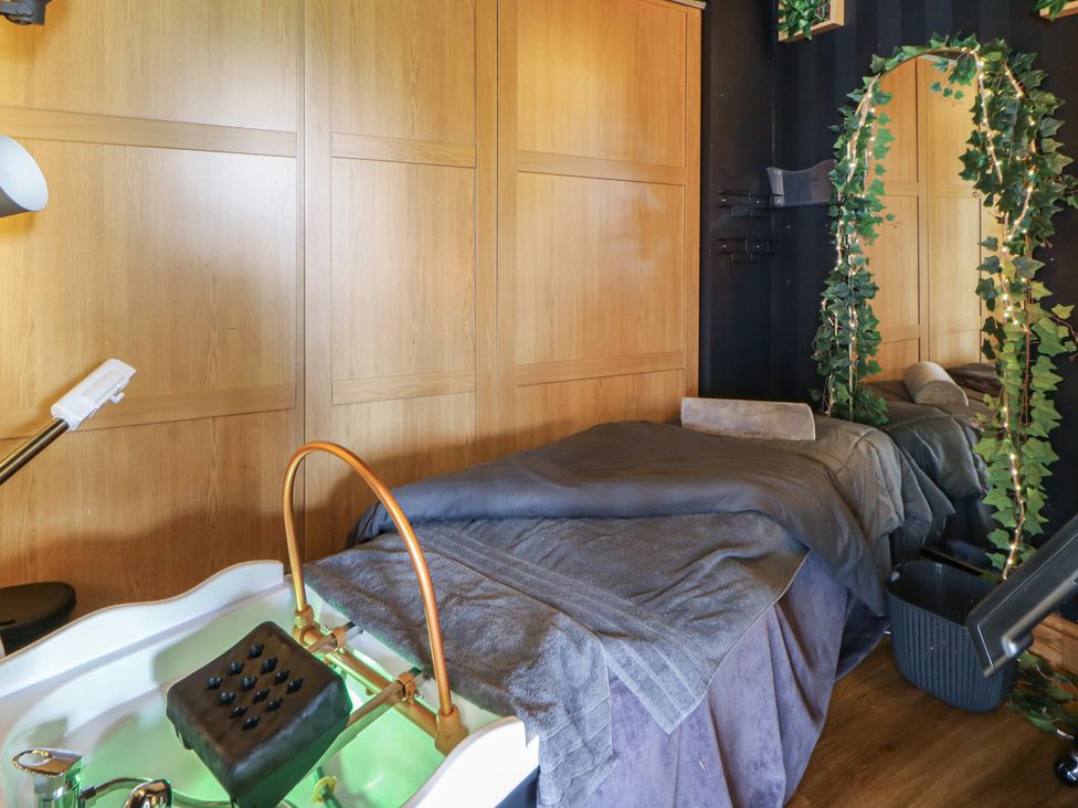 A spa room with a massage table and pedicure basin at The Family Pod in Swansea