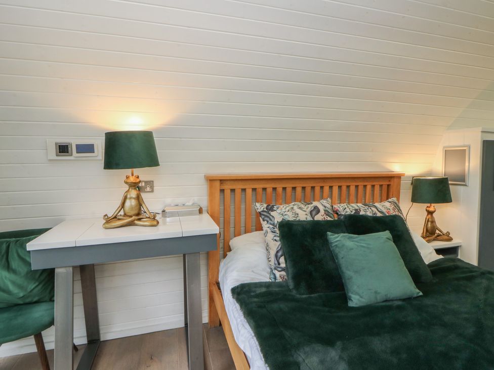 A bedroom with a bed and green accents at Garden Lodge 1 in Swansea
