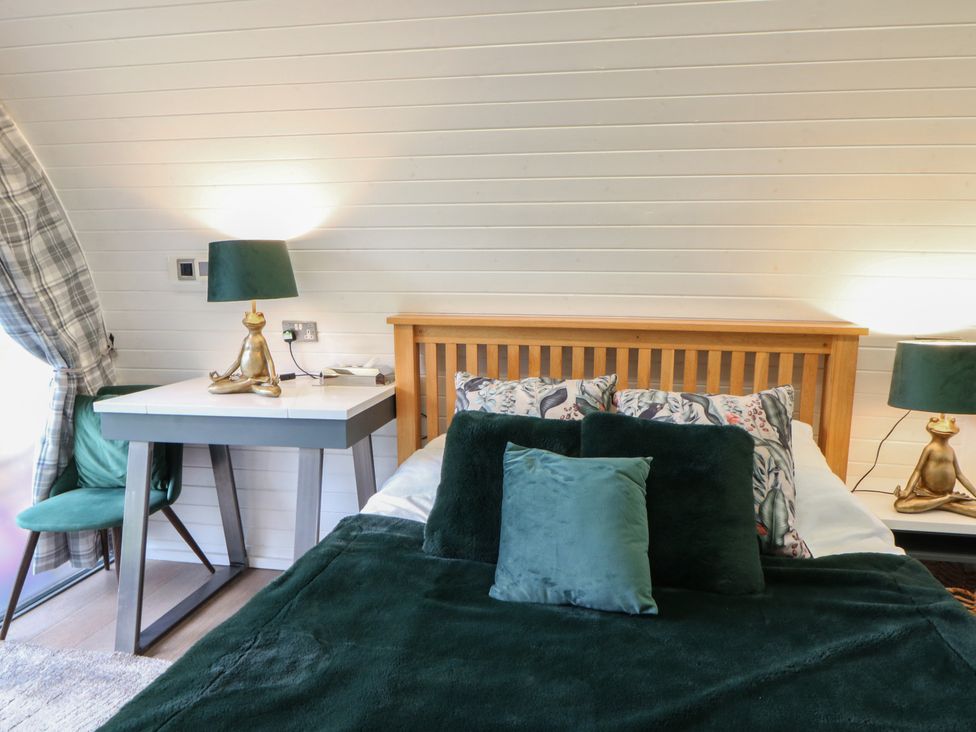 A bedroom with a bed and bedside table at Garden Lodge 1 Swansea
