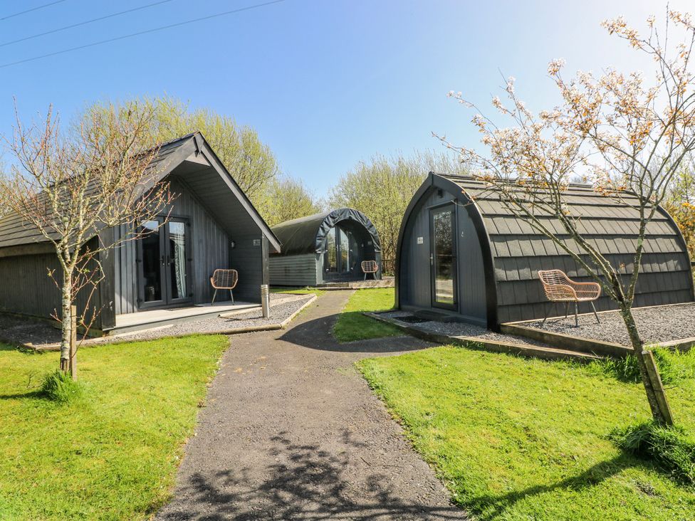 Three glamping pods with a pathway and grass at Glamping Pod 1 Oldwalls, Llanrhidian, Gower