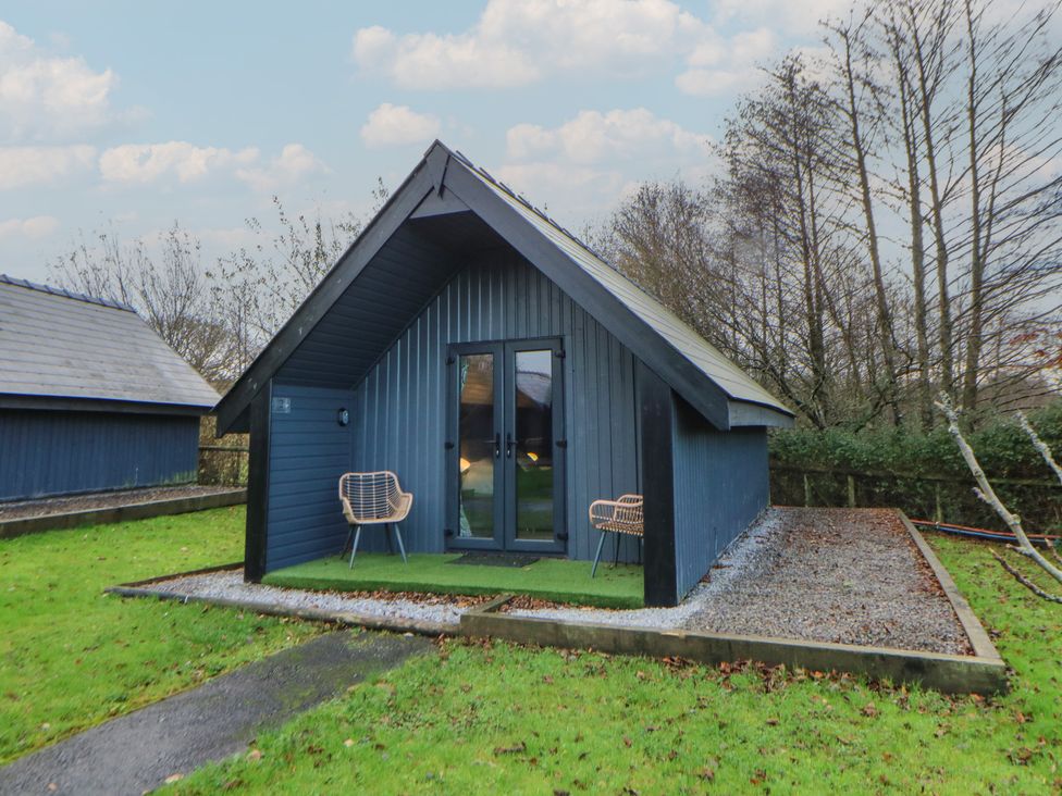 A cottage with chairs and gravel path at Garden Lodge 2 Swansea