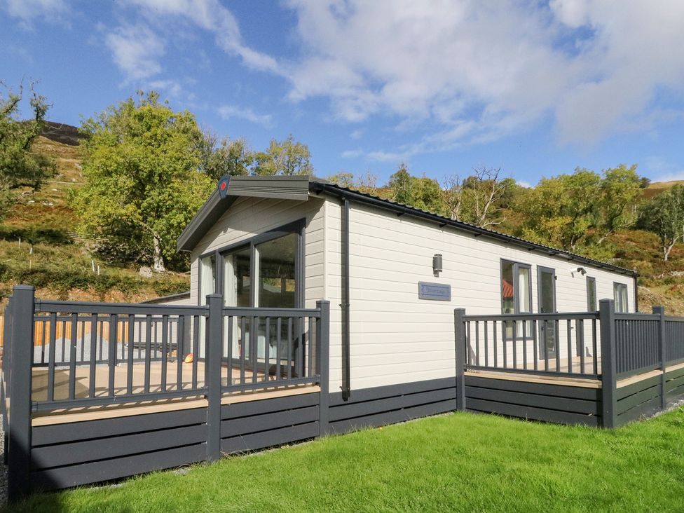 A mobile home with a deck and grass area at Altair Lodge
