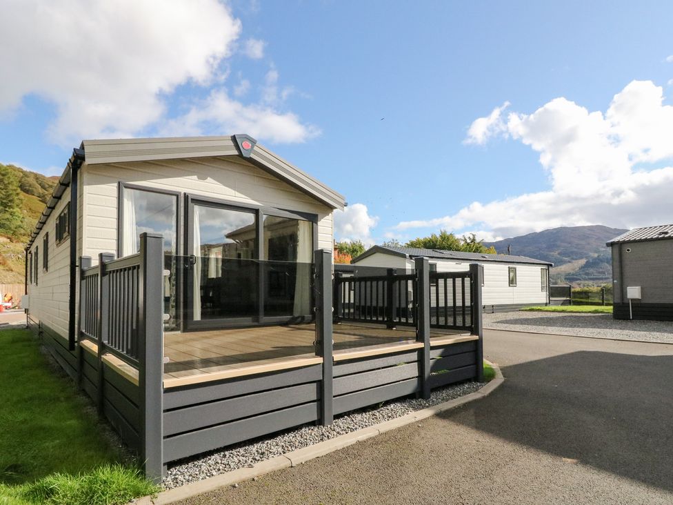 A mobile home with a deck and glass railing at Altair Lodge in 