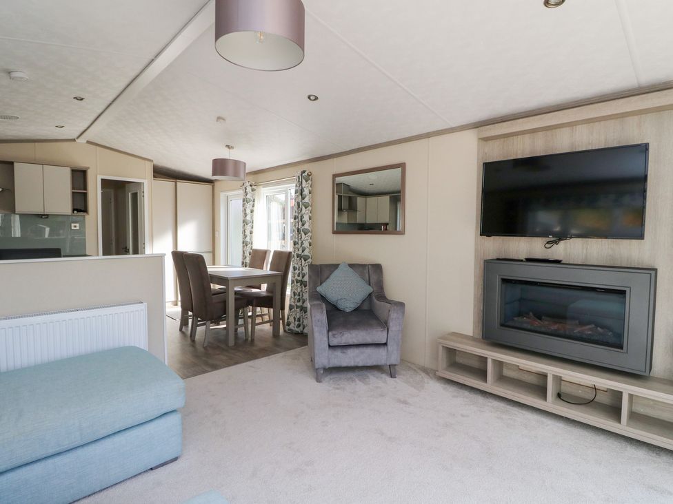A living room with a television and dining area at Altair Lodge