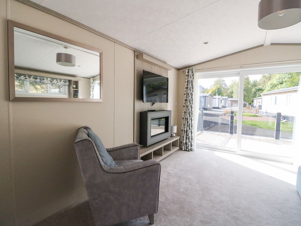 A living room with a chair and television at Altair Lodge