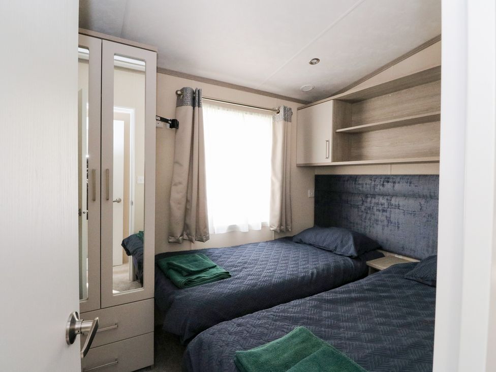 A bedroom with two beds and a wardrobe at Altair Lodge