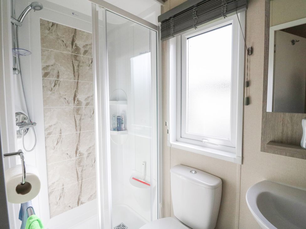 A bathroom with a shower, sink, and toilet at Altair Lodge