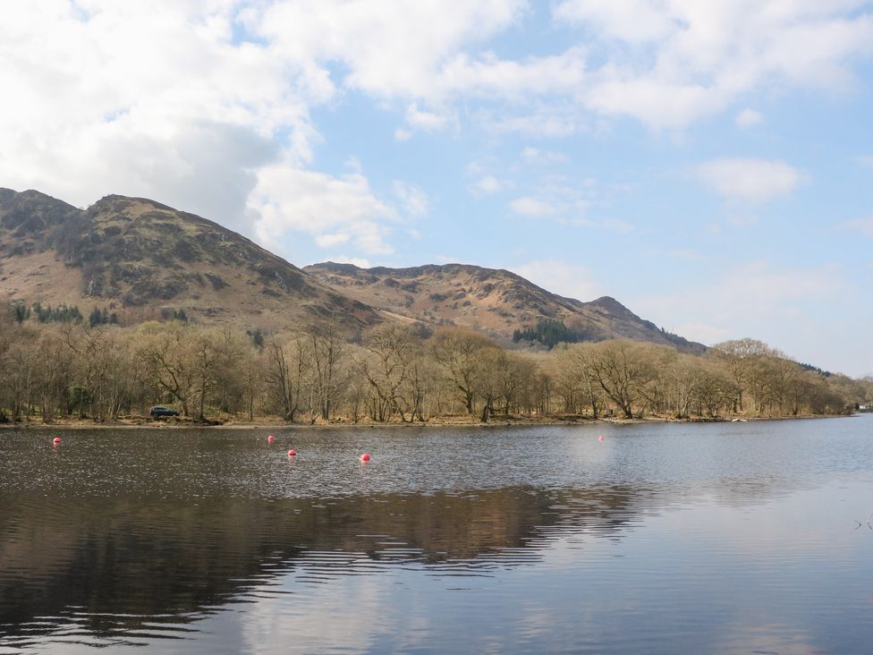A lake with mountains and trees under a blue sky at Altair Lodge