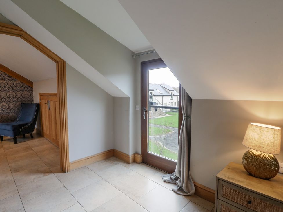A room with a door, a lamp, and a chair at Oak Tree Cottage in Swansea