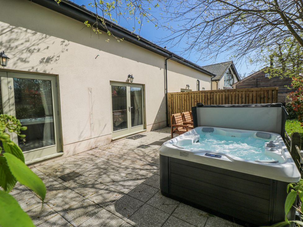 An outdoor area with a hot tub and sliding doors at Oak Tree Cottage, Oldwalls, Llanrhidian, Gower