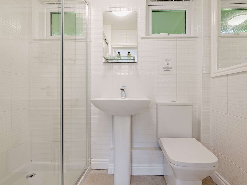 A bathroom with a shower, sink, and toilet at Kernow Nook Spa in Perranporth