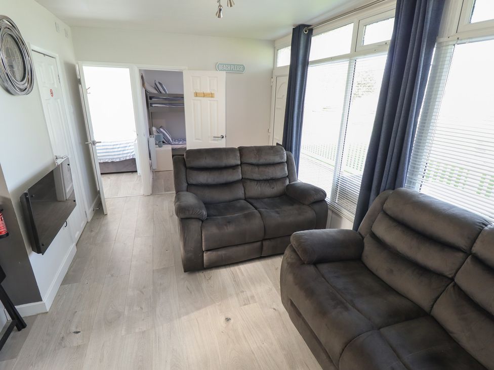 A living room with sofas and a door at No.49 Cherry Park in Chapel St Leonards