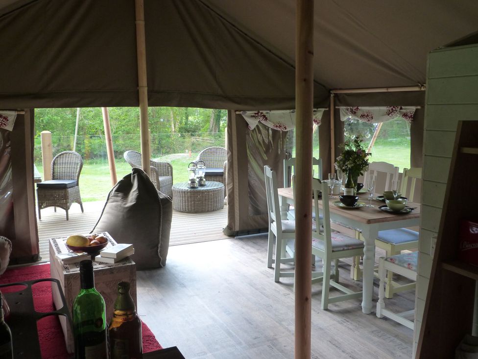 A dining area with a table and chairs in a tent at Ceri Newcastle Emlyn