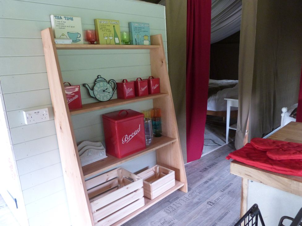 A shelf with containers and a clock in a kitchen at Ceri in Newcastle Emlyn