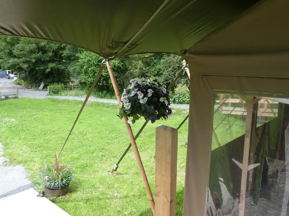 A tent structure with a hanging flower basket at Ceri in Newcastle Emlyn