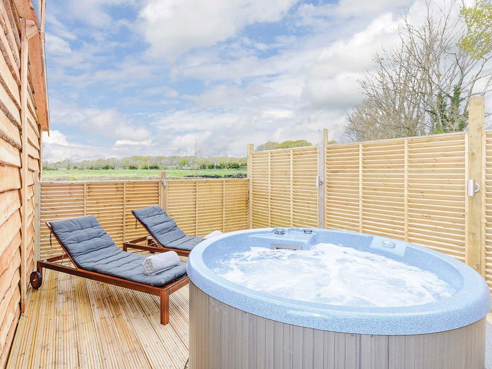 An outdoor area with a hot tub and loungers at Typhoon Lodge in Winchester