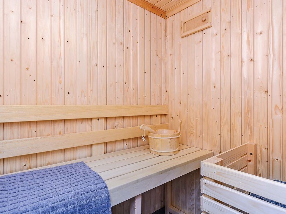 A sauna with wooden bench and bucket at Typhoon Lodge in Winchester