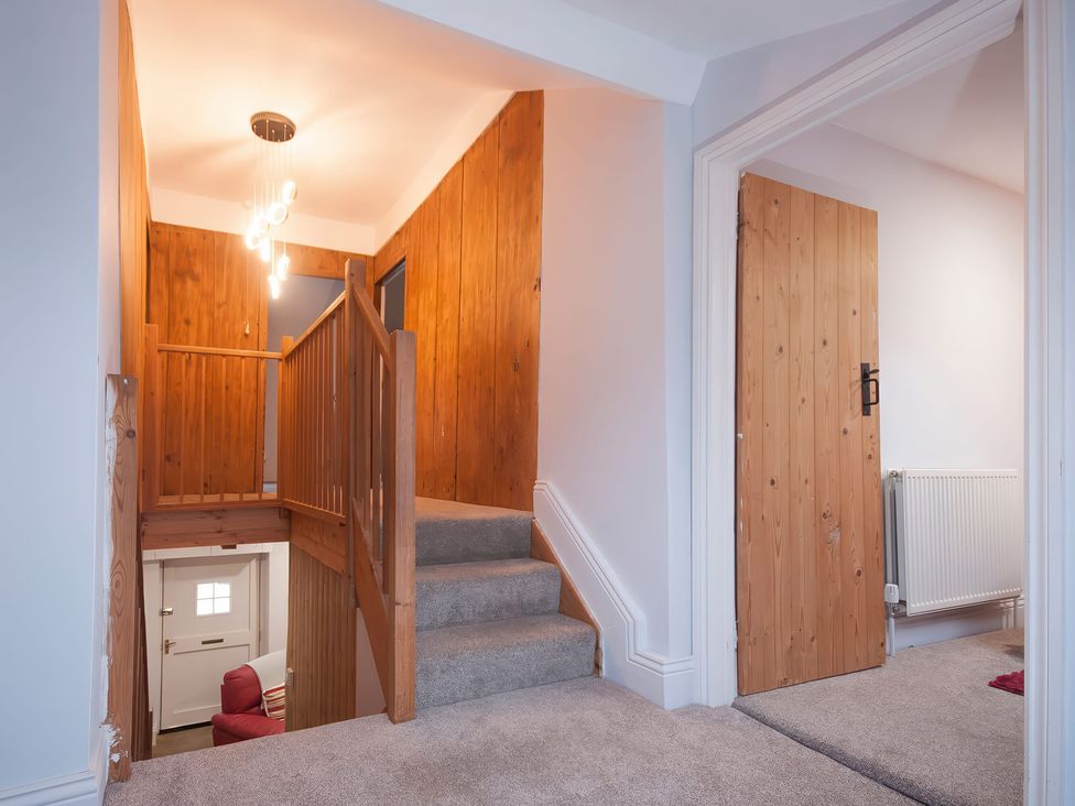 A hallway with a staircase and light fixture at Millers Cottage Newcastle Emlyn