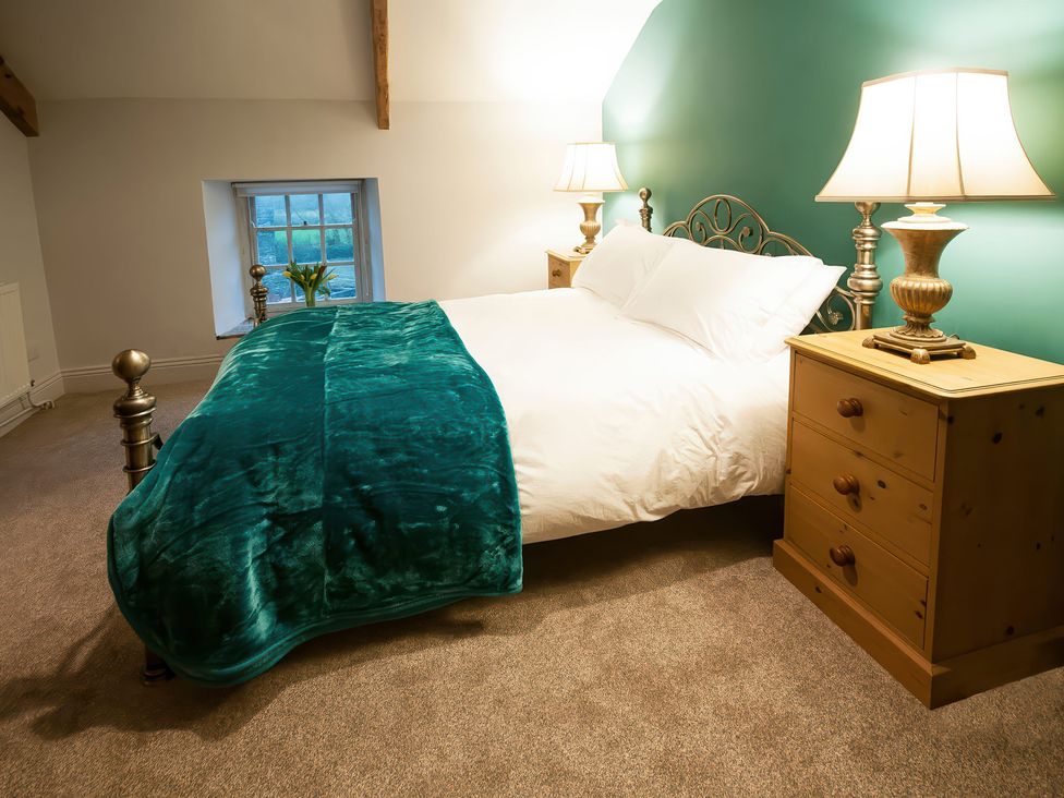 A bedroom with a bed and nightstands at Millers Cottage Newcastle Emlyn
