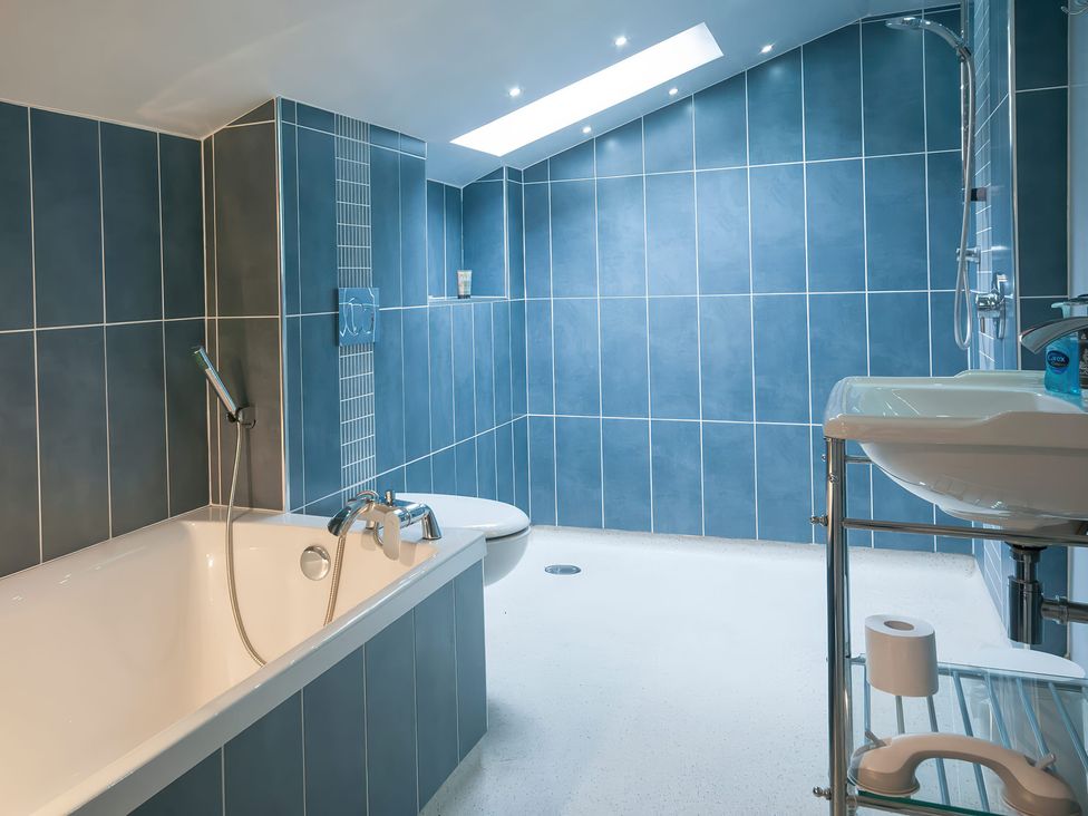 A bathroom with a bathtub and sink at Millers Cottage Newcastle Emlyn