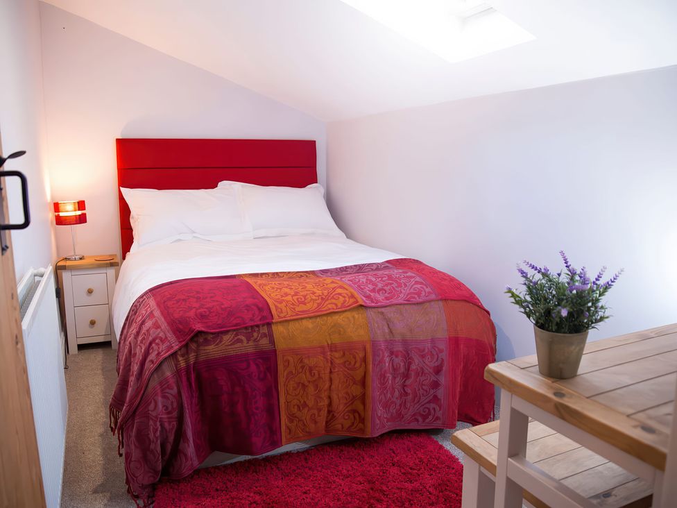 A bedroom with a bed and nightstand at Millers Cottage in Newcastle Emlyn