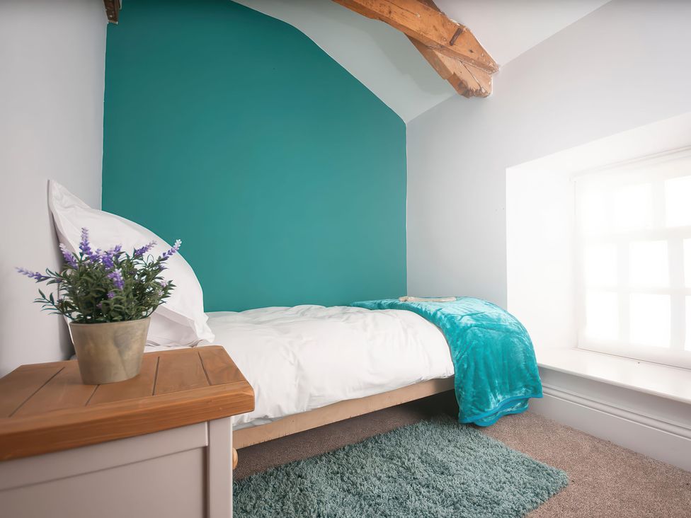 A bedroom with a bed and plant at Millers Cottage Newcastle Emlyn