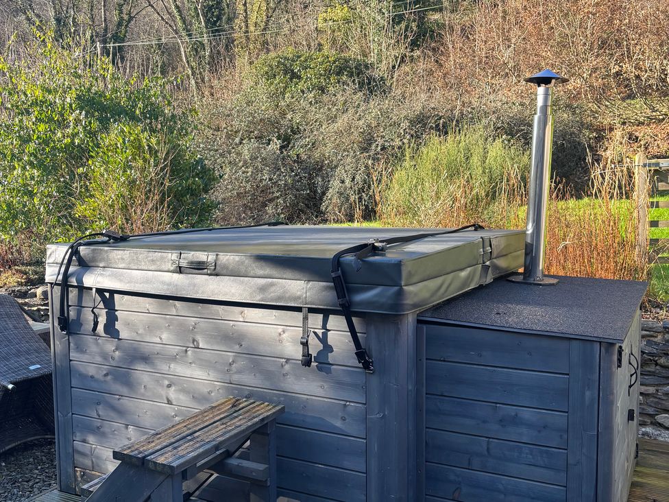 A hot tub with cover and chimney in the garden at Millers Cottage Newcastle Emlyn
