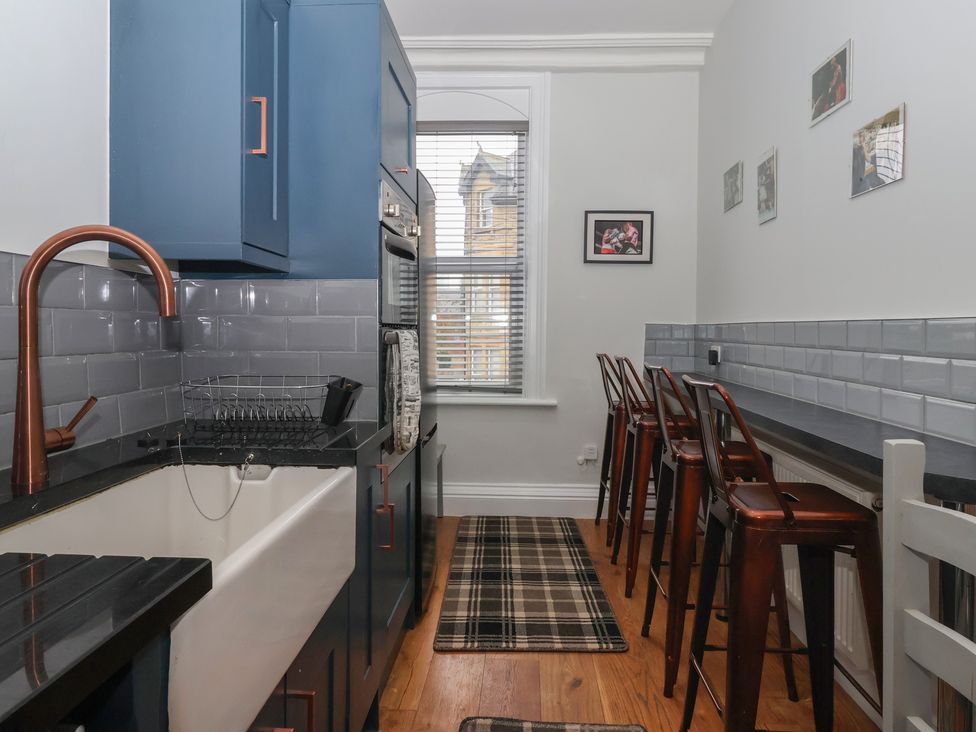 A kitchen with a sink and bar stools at Flat 2 23 Hyde Park Road Harrogate