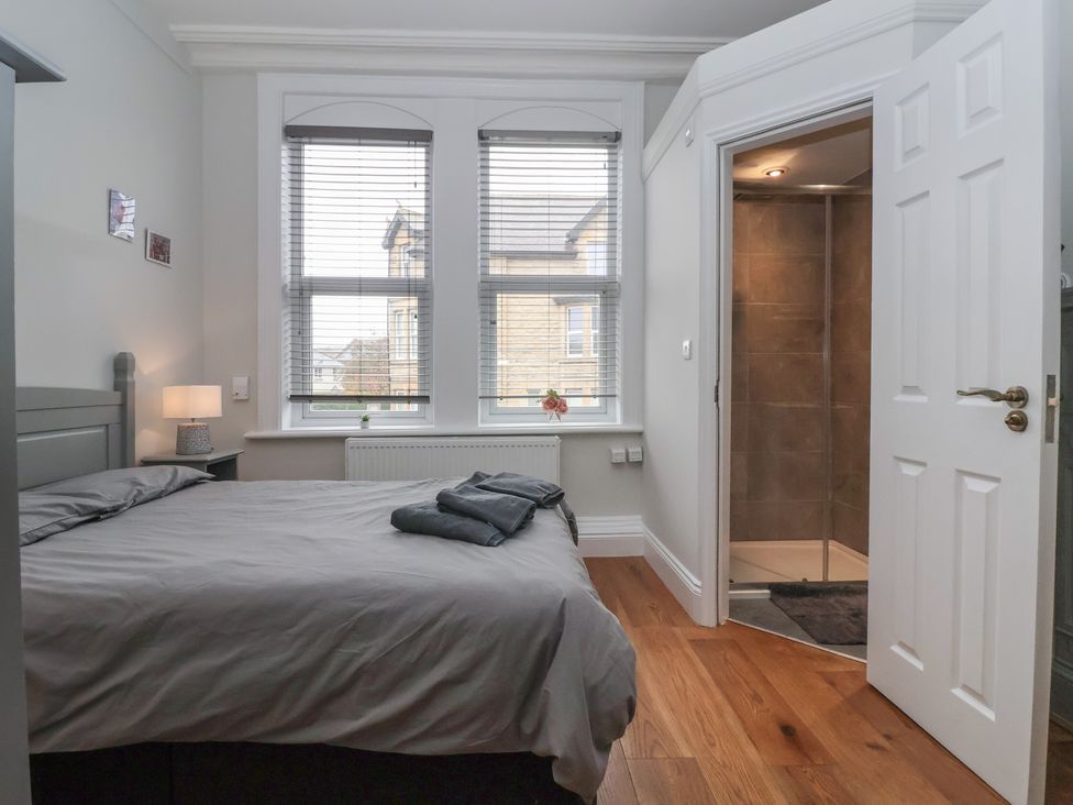 A bedroom with a bed and shower door at Flat 2 23 Hyde Park Road Harrogate