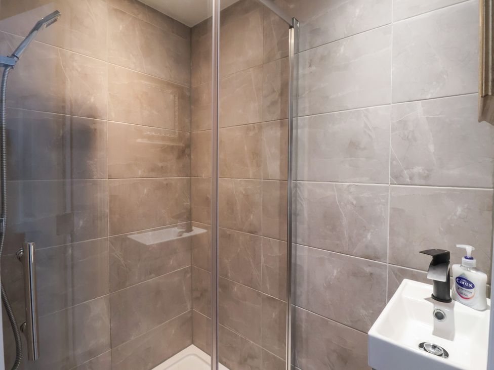 A shower with glass enclosure and sink at Flat 2 23 Hyde Park Road Harrogate