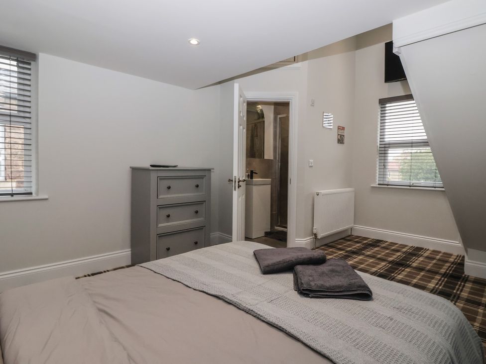 A bedroom with a bed and dresser at Flat 2 23 Hyde Park Road Harrogate