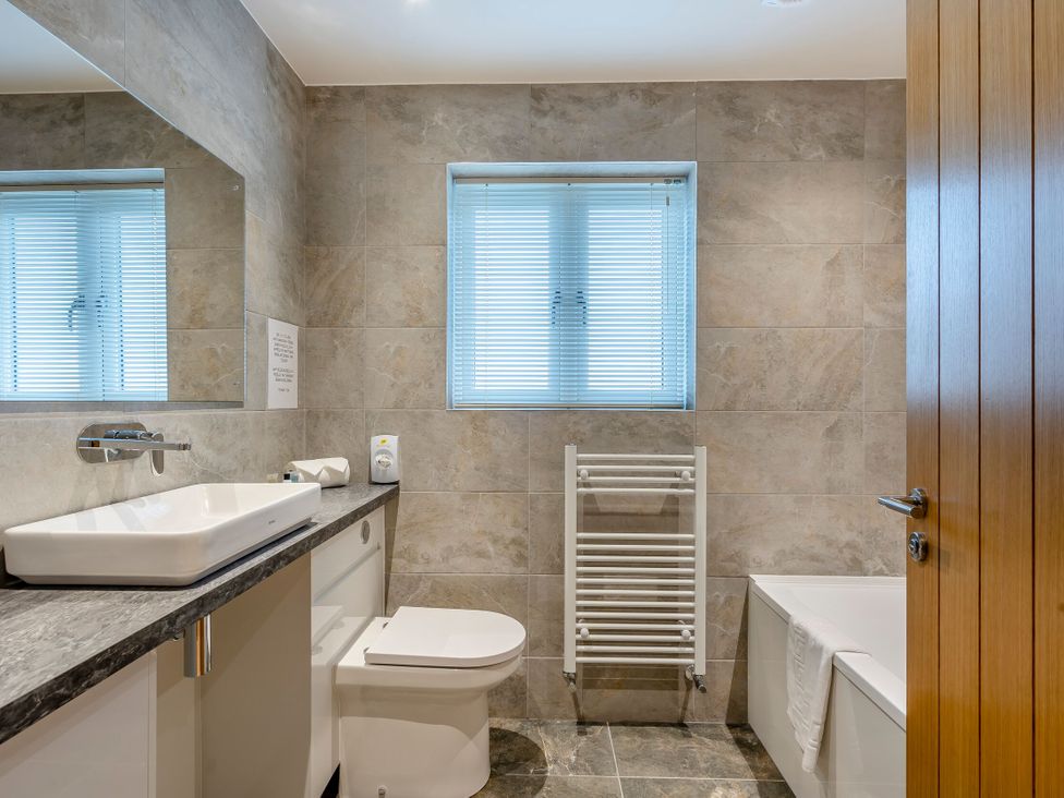 A bathroom featuring a sink, towel radiator, and bathtub at Tranquillity 3 in Warton near Carnforth