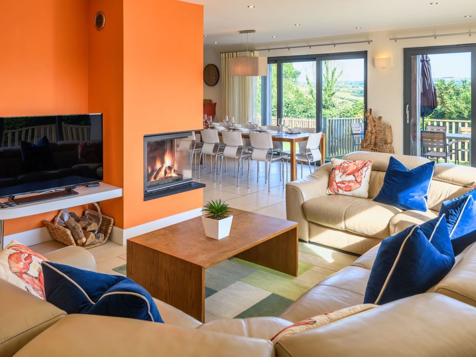 A living room with a fireplace and dining area at Nan's House Spa Marhamchurch