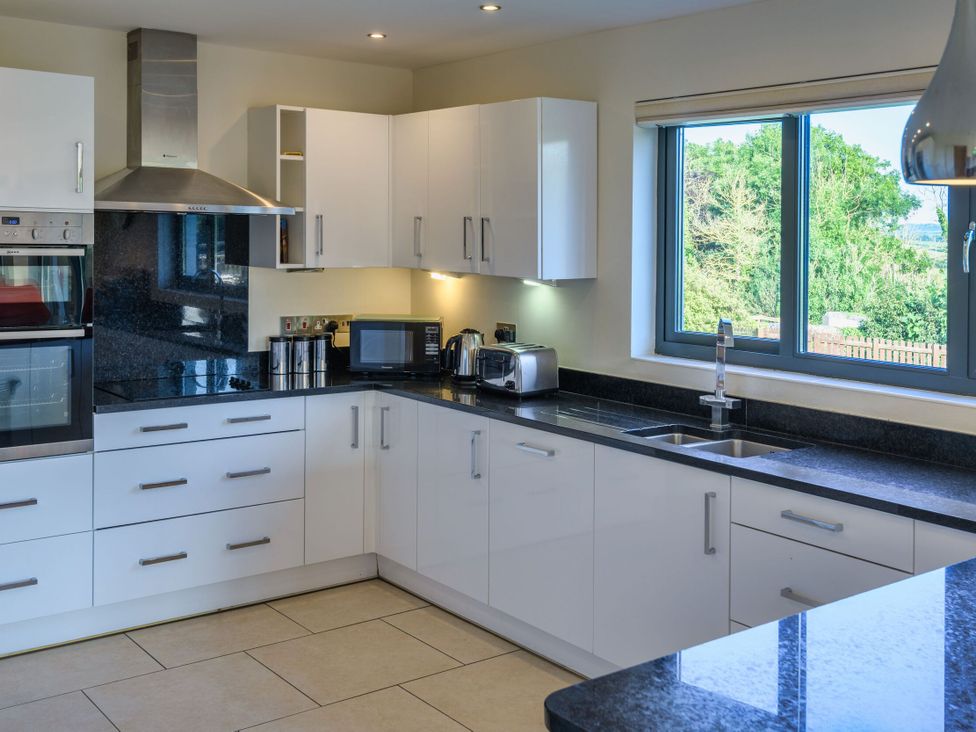 A kitchen with appliances and a window at Nan's House Spa in Marhamchurch