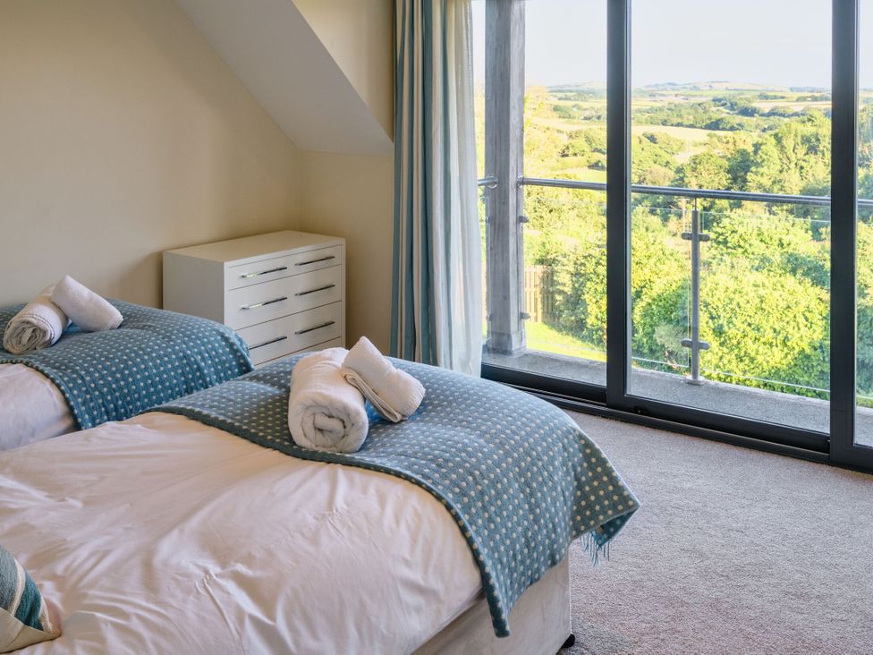 A bedroom with two beds and a window at Nan's House Spa in Marhamchurch