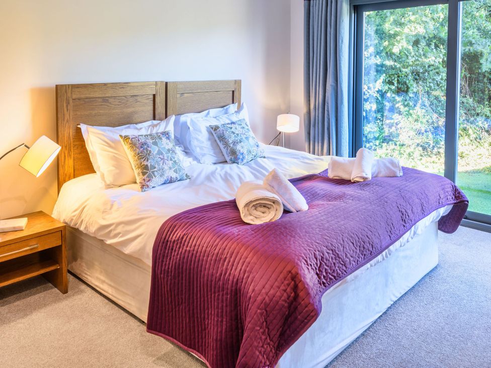 A bedroom with a bed and a sliding door at Nan's House Spa in Marhamchurch