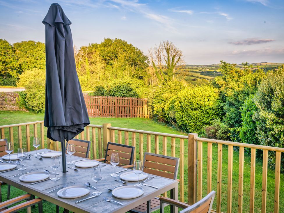 An outdoor dining area with a table and chairs at Nan's House Spa in Marhamchurch