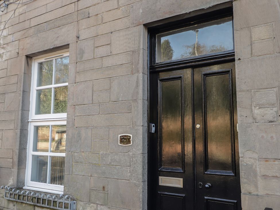 A wooden door and a window on a stone wall at Wee Flat in Avoch