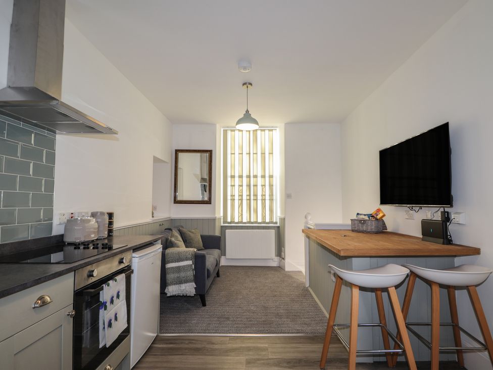 A kitchen with appliances and seating area at Wee Flat in Avoch