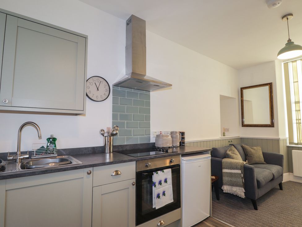 A kitchen with cabinets and a sofa at Wee Flat in Avoch