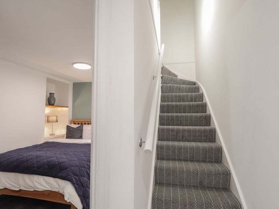 A bedroom with a bed and stairs at Wee Flat in Avoch