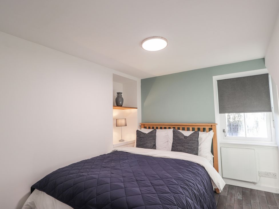 A bedroom with a bed and shelf at Wee Flat in Avoch