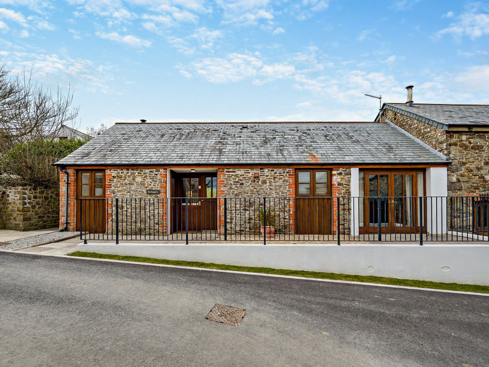 A house with a stone exterior and fence at Barley Park in Marhamchurch